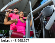 Lat Lateral dorsal pulldown machine upper back woman with personal trainer man. Стоковое фото, агентство Ingram Publishing / Фотобанк Лори
