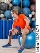 dumbbell concentrated biceps curl  man workout at gym sit on swiss ball fitball. Стоковое фото, агентство Ingram Publishing / Фотобанк Лори