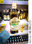 Оливковое масло Extra Virgin от Filippo Berio в руке мужчины в супермаркете. Редакционное фото, фотограф FotograFF / Фотобанк Лори