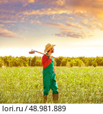 Farmer man with hoe looking at his orchard field with hat. Стоковое фото, агентство Ingram Publishing / Фотобанк Лори
