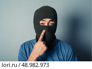 A stupid man wearing a balaclava is trying to pick his nose. Стоковое фото, агентство Ingram Publishing / Фотобанк Лори