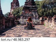 A young woman is sitting and meditating amongst the ruins of an ancient buddhist temple. Стоковое фото, агентство Ingram Publishing / Фотобанк Лори