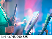 A blurred musical background in which hands hold a saxaphone in front of a staff. Musical poster or advertisement for a brass concert. Стоковое фото, фотограф Лазаренко Светлана / Фотобанк Лори
