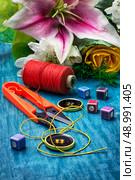 sewing accessories with a bouquet of fresh flowers on turquoise background. Стоковое фото, агентство Ingram Publishing / Фотобанк Лори