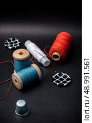 thread and buttons for sewing master on black background.Selective focus. working tool dressmaker. Стоковое фото, агентство Ingram Publishing / Фотобанк Лори