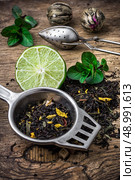 scattered on wooden table tea leaves and tea strainer.Selective focus. tea leaves. Стоковое фото, агентство Ingram Publishing / Фотобанк Лори