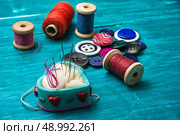 thread buttons for crafts on turquoise wooden background. working tool dressmaker. Стоковое фото, агентство Ingram Publishing / Фотобанк Лори