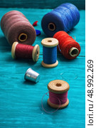 thread buttons for crafts on turquoise wooden background.Selective focus. working tool dressmaker. Стоковое фото, агентство Ingram Publishing / Фотобанк Лори