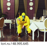 the man in a protective coverall sitting in an empty restaurant with a drink. Photo combination creative concept. Стоковое фото, агентство Ingram Publishing / Фотобанк Лори