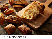 Bread varied loafs sliced on wood board in rustic wood table. Стоковое фото, агентство Ingram Publishing / Фотобанк Лори