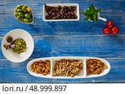 Mediterranean tapas black olives capers and nuts on blue wood table. Стоковое фото, агентство Ingram Publishing / Фотобанк Лори