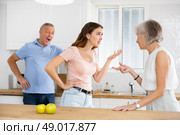 Quarrel between an elderly mother and an adult daughter in home kitchen. Father tries to calm everyone. Стоковое фото, фотограф Яков Филимонов / Фотобанк Лори