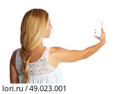 Blond tourist girl taking photos with smartphone on white background and braid. Стоковое фото, агентство Ingram Publishing / Фотобанк Лори