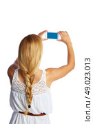Blond tourist girl taking photos with smartphone on white background and braid. Стоковое фото, агентство Ingram Publishing / Фотобанк Лори