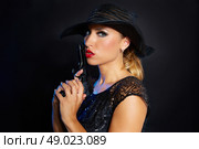 Fashion woman gangster style with handgun pistol on black background. Стоковое фото, агентство Ingram Publishing / Фотобанк Лори