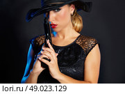 Fashion woman gangster style with handgun pistol on black background. Стоковое фото, агентство Ingram Publishing / Фотобанк Лори