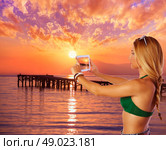 Blond tourist girl taking photos of Mallorca Alcudia beach sunset photomount. Стоковое фото, агентство Ingram Publishing / Фотобанк Лори