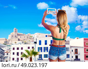 Blond tourist girl taking photos of Ibiza skyline photomount. Стоковое фото, агентство Ingram Publishing / Фотобанк Лори
