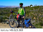 cycling tourist MTB cyclist in Pedralba Valencia with paniers and saddlebag Spain. Стоковое фото, агентство Ingram Publishing / Фотобанк Лори