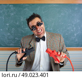 Nerd electronics technician retro teacher silly expression working battery clamps. Стоковое фото, агентство Ingram Publishing / Фотобанк Лори