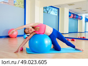 Pilates woman side bend fitball exercise workout at gym indoor swiss ball. Стоковое фото, агентство Ingram Publishing / Фотобанк Лори