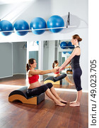 pregnant woman pilates exercise with spine wave corrector and personal trainer. Стоковое фото, агентство Ingram Publishing / Фотобанк Лори