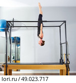Pilates woman in cadillac acrobatic upside down balance reformer exercise at gym. Стоковое фото, агентство Ingram Publishing / Фотобанк Лори