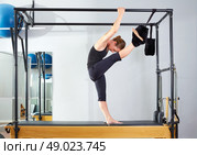 Pilates woman in cadillac split legs stretch exercise at gym. Стоковое фото, агентство Ingram Publishing / Фотобанк Лори