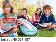 Group of little students sitting on the grass at school. Стоковое фото, агентство Ingram Publishing / Фотобанк Лори