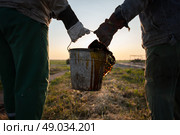 Workers carry a bucket of spilled extracted oil. Discover oil fields. Black gold. Стоковое фото, фотограф Лазаренко Светлана / Фотобанк Лори
