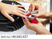 Nails painting with UV dry lamp in blue light woman hands at nail salon. Стоковое фото, агентство Ingram Publishing / Фотобанк Лори