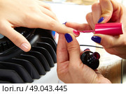 Nails painting with UV dry lamp in blue light woman hands at nail salon. Стоковое фото, агентство Ingram Publishing / Фотобанк Лори