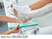Pedicure nourishing moisturizer mask legs cling film wrap heat effect in nail salon. Стоковое фото, агентство Ingram Publishing / Фотобанк Лори