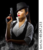 Portrait of young woman in manly style with gun and smoke. Стоковое фото, агентство Ingram Publishing / Фотобанк Лори