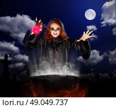 Young witch with red potion and cauldron on night sky background. Стоковое фото, агентство Ingram Publishing / Фотобанк Лори