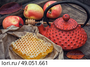 Still life with honeycombs. Honeycomb wrapped in grey paper on the background of the red kettle. Стоковое фото, агентство Ingram Publishing / Фотобанк Лори