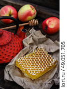 Still life with honeycombs. Honeycomb wrapped in grey paper on the background of the red kettle. Стоковое фото, агентство Ingram Publishing / Фотобанк Лори