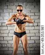 Muscular sporty woman on grey brick wall (normal version) Стоковое фото, агентство Ingram Publishing / Фотобанк Лори