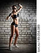 Muscular woman on grey brick wall (dark version) Стоковое фото, агентство Ingram Publishing / Фотобанк Лори