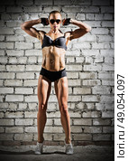 Muscular woman on grey brick wall (dark version) Стоковое фото, агентство Ingram Publishing / Фотобанк Лори