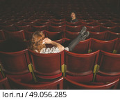A young woman is talking on her phone in an auditorium and is annoying a man a few rows in front of her. Стоковое фото, агентство Ingram Publishing / Фотобанк Лори