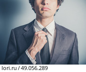 A young businessman his adjusting his tie. Стоковое фото, агентство Ingram Publishing / Фотобанк Лори