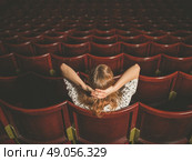 Rear view shot of a young woman sitting alone in an auditorium. Стоковое фото, агентство Ingram Publishing / Фотобанк Лори