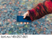 A young woman is using her smartphone outside with gravel and rubble on the ground. Стоковое фото, агентство Ingram Publishing / Фотобанк Лори