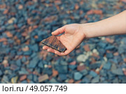 A womans hand is holding a piece of slate outside with gravel and rubble on the ground. Стоковое фото, агентство Ingram Publishing / Фотобанк Лори