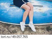 A young woman wearing a blue dress is sitting on an upturned boat on the beach. Стоковое фото, агентство Ingram Publishing / Фотобанк Лори