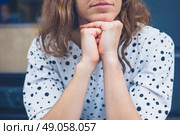 A young woman is sitting with her head resting on her hands and daydreaming. Стоковое фото, агентство Ingram Publishing / Фотобанк Лори