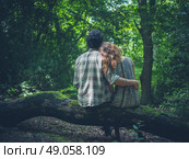 A young couple is sitting on a log in the forest and embracing. Стоковое фото, агентство Ingram Publishing / Фотобанк Лори