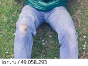 A trendy young man with a hole torn in his jeans at the knee is sitting on the grass. Стоковое фото, агентство Ingram Publishing / Фотобанк Лори