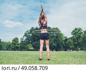 A fit and athletic young woman is working out with a hula hoop in the park on a sunny summer day. Стоковое фото, агентство Ingram Publishing / Фотобанк Лори